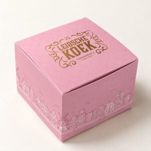 Roze kartonnen koekdoos van Leidsche Koek met gouden logo en de Leidse gevels